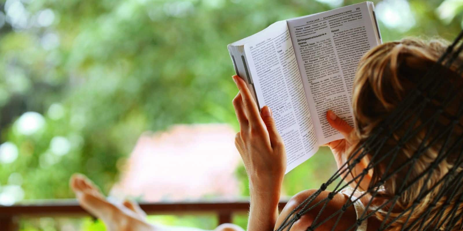 Frau entspannt in einer Hängematte und liest ein Buch – Inspiration für Tipps zum Stressabbau und einen stressfreien Alltag.