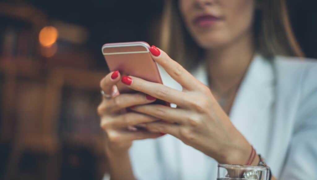 Frau hält Smartphone achtsam in der Hand, Fokus auf bewussten Medienkonsum.