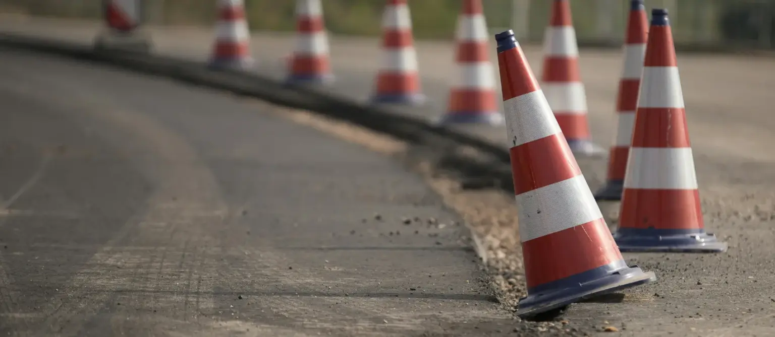 Eine Reihe rot-weißer Leitkegel auf Asphalt als klares Zeichen für das Grenzen setzen.